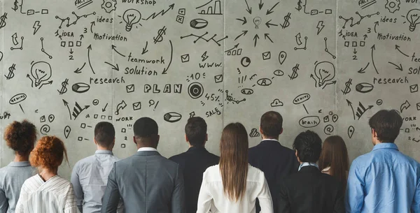 Grupo de personas mirando a la pared gris con dibujos motivacionales —  Fotos de Stock