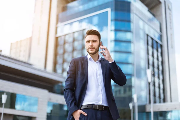 Executivo de negócios atraente falando no celular em frente ao prédio de vários andares — Fotografia de Stock