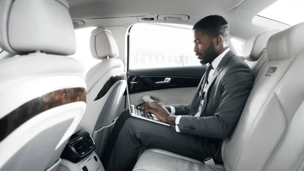 Empresário preto usando laptop trabalhando no carro durante passeio, Panorama — Fotografia de Stock