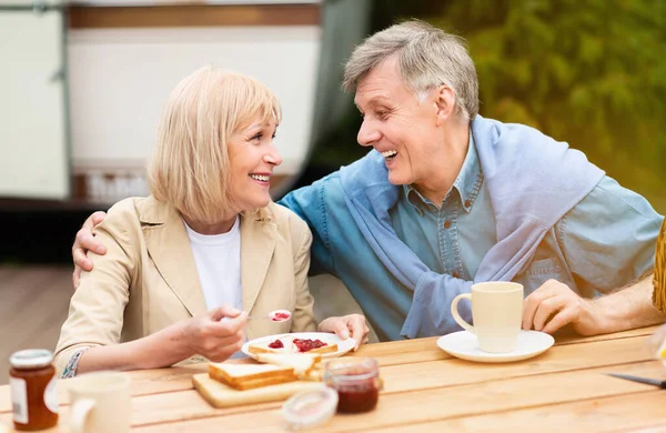 Amar pareja de ancianos teniendo tostadas con mermelada para el desayuno en el camping —  Fotos de Stock