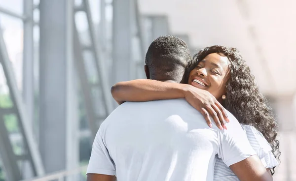 Długo oczekiwane spotkanie. Szczęśliwa Afroamerykanka obejmująca męża na lotnisku — Zdjęcie stockowe