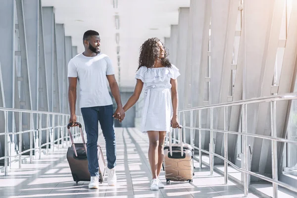Reinício do voo. Feliz casal preto de viajantes caminhando no aeroporto termina — Fotografia de Stock