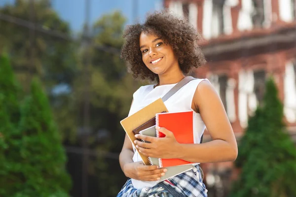 Studentisches Orientierungskonzept. Glücklich schwarz teen mädchen holding workbooks posieren im freien — Stockfoto