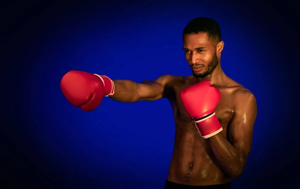 Boxeador afroamericano que usa guantes de pie sobre fondo azul — Foto de Stock