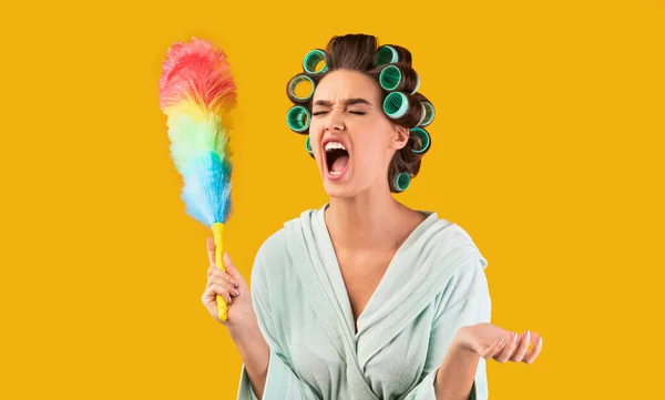 Hausfrau schreit Holding Feather Duster, müde von Reinigung, gelber Hintergrund — Stockfoto