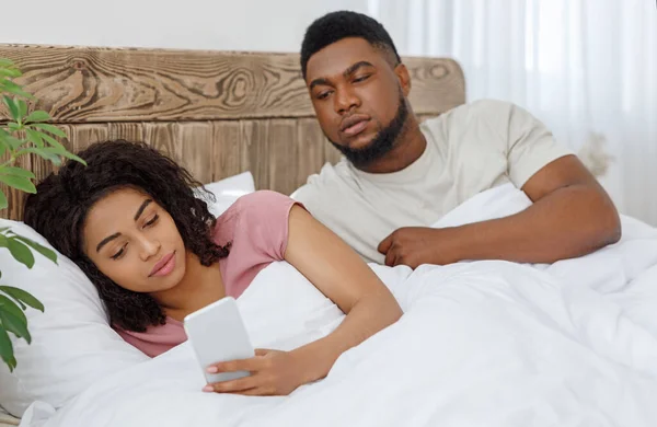 Zwart meisje chatten met minnaar op mobiele telefoon in bed — Stockfoto