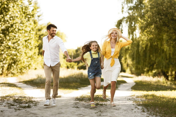 Happy Family Of Three Running Enjoying Outdoor Walk In Countryside