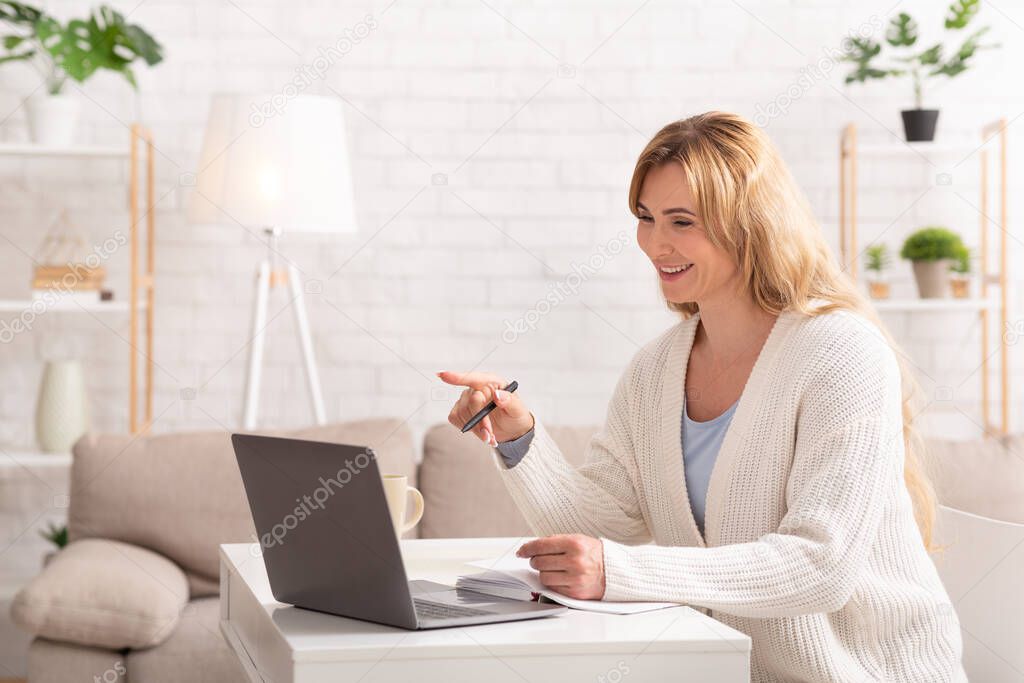 Skype lessons. Woman is teaching online, sitting at table,