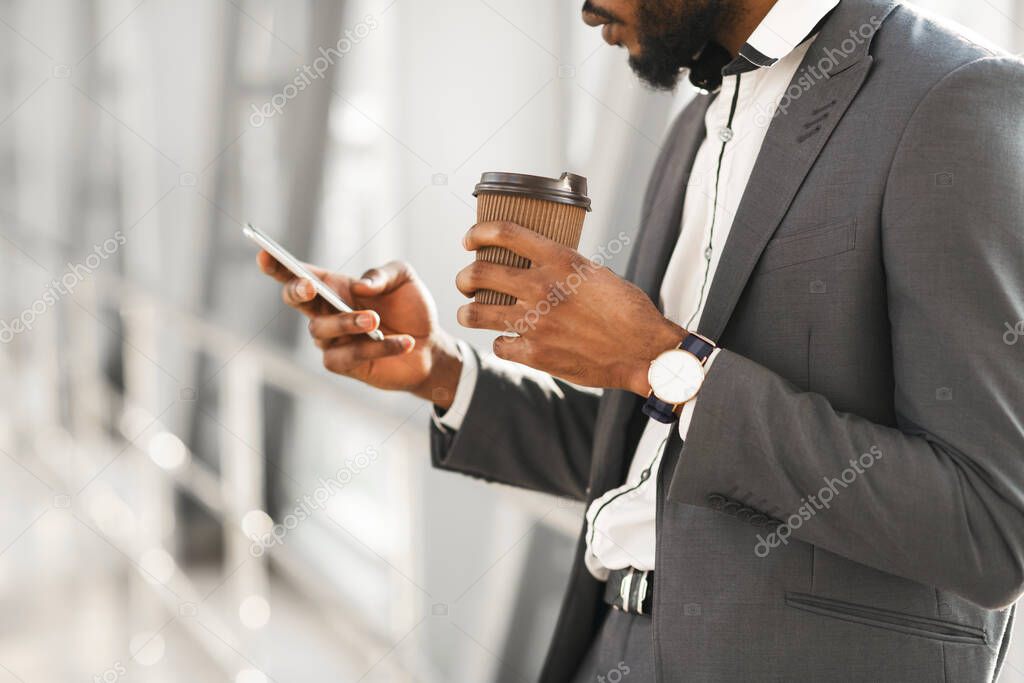 Unrecognizable Businessman Using Smartphone Having Coffee Standing In Airport, Cropped