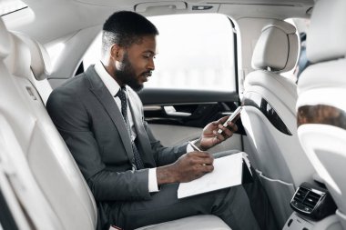 Akıllı Telefon Kullanan İşadamı Not Alırken Arabada Oturma Planı Yapıyor