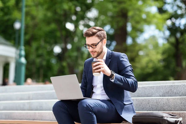 Executivo corporativo em desgaste formal sentado em escadas no parque com laptop e café durante a pausa para almoço — Fotografia de Stock