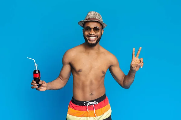 KHARKIV, UCRANIA 31 de marzo. 2019: Guapo africano en traje de baño disfrutando de una refrescante bebida de Coca Cola —  Fotos de Stock