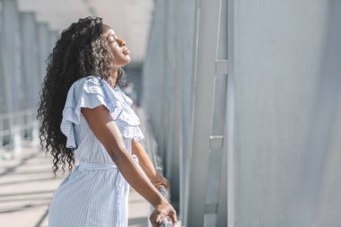 Havaalanı terminalinde gözleri kapalı duran genç siyahi kadının yan görüntüsü