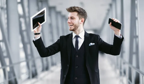 Hombre de negocios urbano sosteniendo teléfono y tableta — Foto de Stock