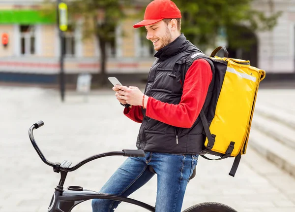 Şehirde Bisikletle Restoran Yemeği Teslim Etmek İçin Akıllı Telefon Kullanan Kurye — Stok fotoğraf