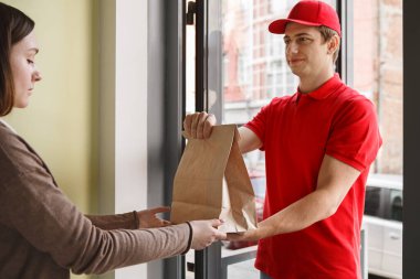 Fast food teslimatı. Kız, kuryeden sipariş ile kese kağıdı alır.