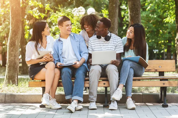 Отдых для студентов. Друзья по колледжу отдыхают в кампусе на открытом воздухе, используют ноутбук вместе — стоковое фото
