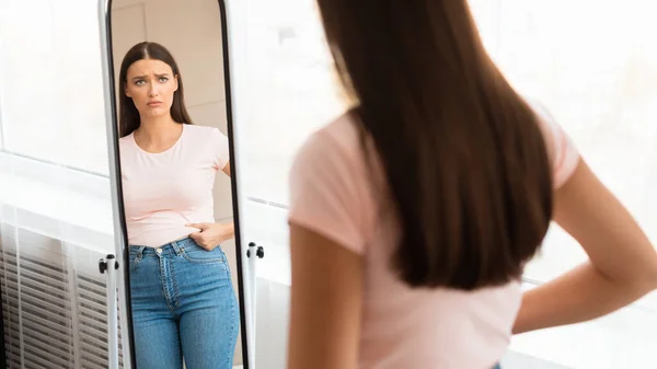 Femme bouleversée touchant gros ventre regardant dans le miroir intérieur, Panorama — Photo