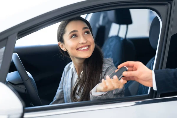 Mädchen nimmt Schlüssel vom Verkäufer für Testfahrt — Stockfoto