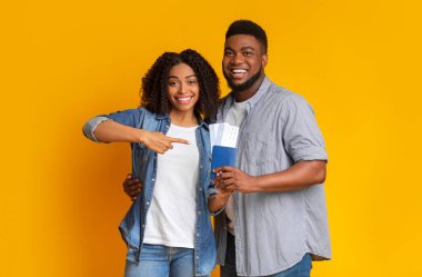 Mutlu Afro-Amerikan çifti ellerinde biletlerle pasaportlarını gösteriyorlar.