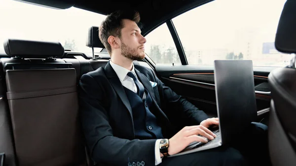 在豪华轿车上使用笔记本电脑的年轻商人 — 图库照片