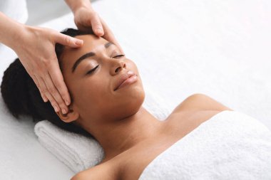 Siyah kadın spa salonunda kafa masajı yaptırıyor.