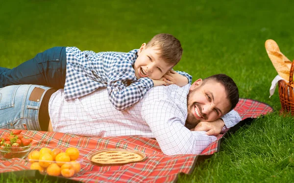 Vinculación familiar. Lindo niño acostado sobre sus papás durante el picnic en el campo — Foto de Stock