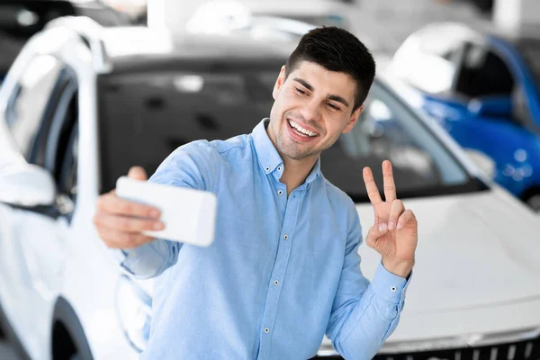 Bonito sorrindo cara fazendo selfie na concessionária — Fotografia de Stock