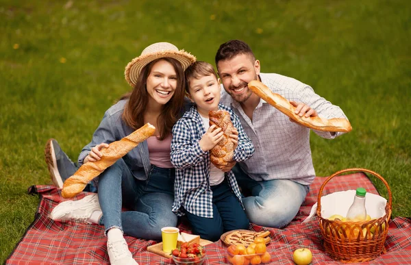 Eğlenceli aile zamanları. Milenyum erkeği eşi ve çocuğu bahçede piknikte eğleniyor. — Stok fotoğraf