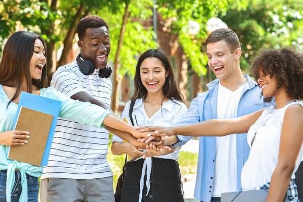 Gruppo di amici universitari accatastamento mani all'aperto dopo il successo degli esami Pass — Foto Stock