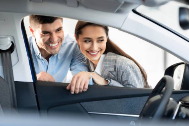 Güzel gülümseyen bir çift satın almadan önce arabayı inceliyor.