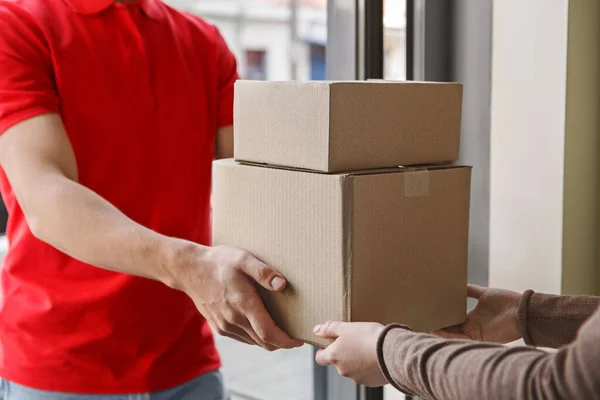 Recebendo parcela em casa. Courier dá caixas de papelão ao cliente — Fotografia de Stock