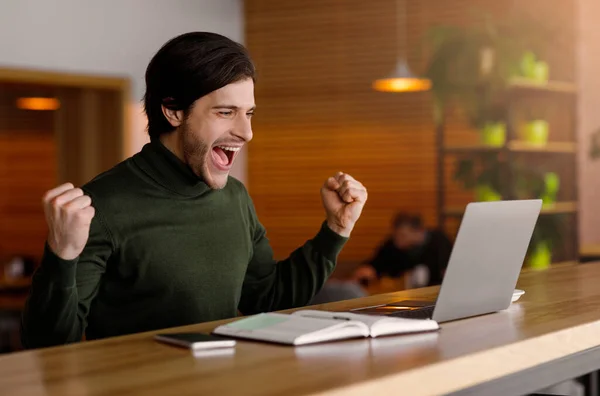 Emotionele man kijkt naar laptop en schreeuwt, werkt in café — Stockfoto