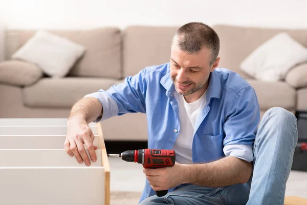 自宅で電気ドリルを使用して家具の修理キャビネットを固定する男 — ストック写真