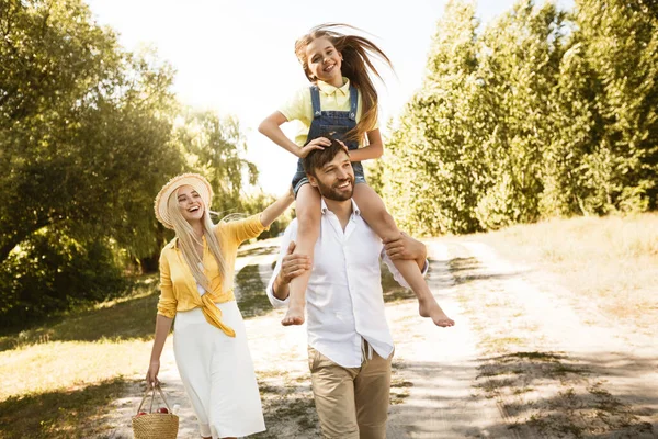 Joyeux papa portant petite fille pendant la promenade en famille dans la campagne — Photo