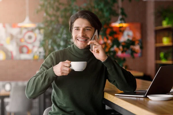 Joven alegre que trabaja con el ordenador portátil en la cafetería — Foto de Stock