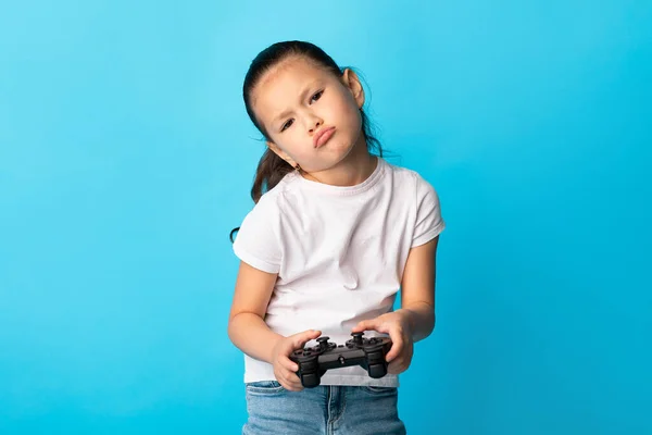 Unhappy asiatisch kid playing videospiel using joystick — Stockfoto