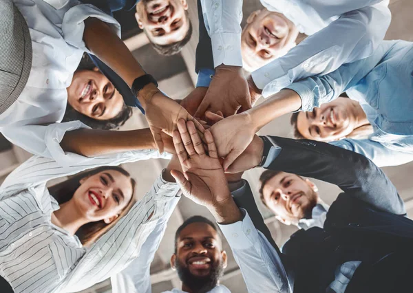 Felices compañeros de trabajo sosteniendo las manos durante la reunión de trabajo en equipo de pie en el cargo —  Fotos de Stock