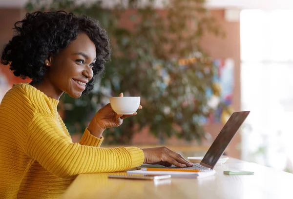 Femme noire buvant du café et souriant à quelqu'un au café — Photo