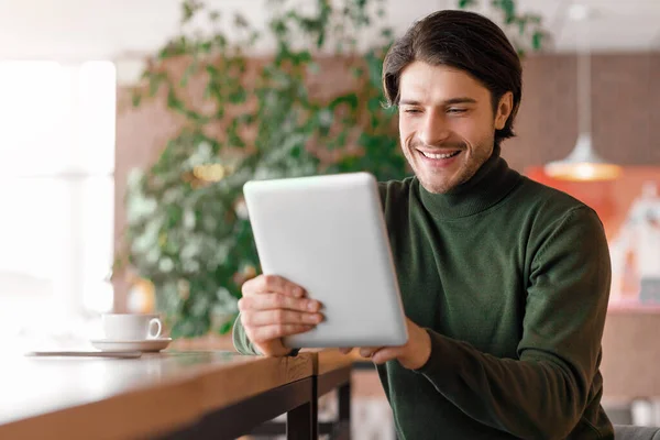 Vrolijke man maakt videogesprek via digitale tablet, cafe interieur — Stockfoto