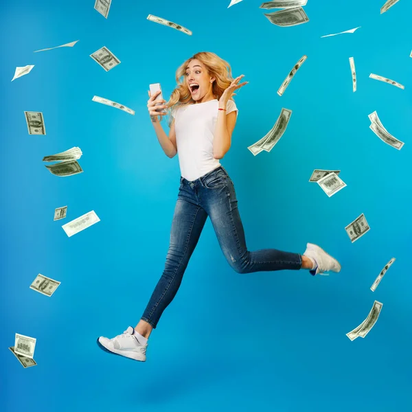 Loteria online. Mulher feliz pulando com smartphone sob chuveiro de dinheiro, celebrando a vitória — Fotografia de Stock