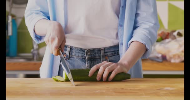 Профессиональный повар режет свежий огурец на доске — стоковое видео