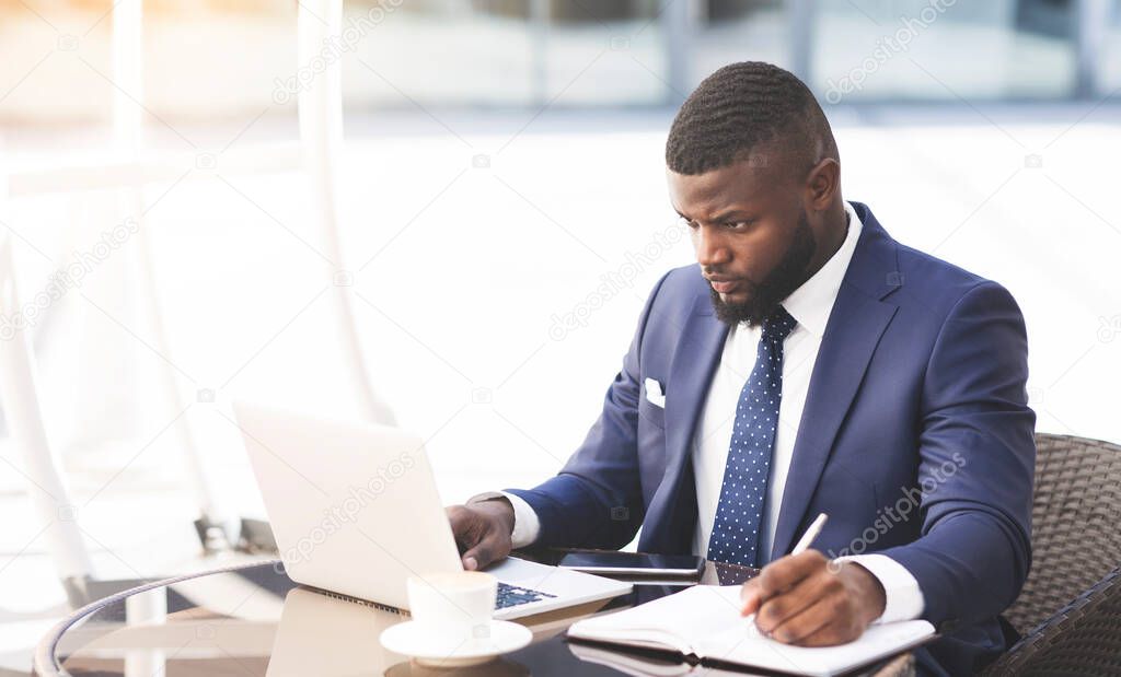 Serious Entrepreneur Using Laptop Taking Notes Working In Outdoor Cafe