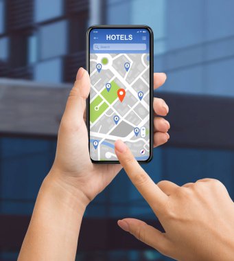 Şehir caddesinde cep telefonundaki otelleri aramak için mobil GPS navigasyon uygulaması kullanan kolaj kızı, yakın plan