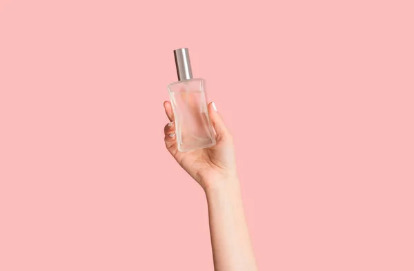 Ausgeschnittene Ansicht eines jungen Mädchens mit einer Flasche Parfüm auf rosa Hintergrund, Nahaufnahme der Hand — Stockfoto