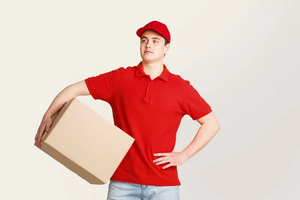 Deliveryman expectation customer at door. Courier looks at free space and holds big box under his arm — Stock Photo, Image