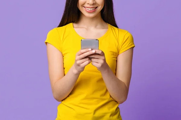 紫の背景に立って認識できないアジアの女の子の手の中に現代のスマートフォン — ストック写真