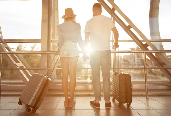 Vista posteriore della coppia in piedi in aeroporto con bagagli — Foto Stock