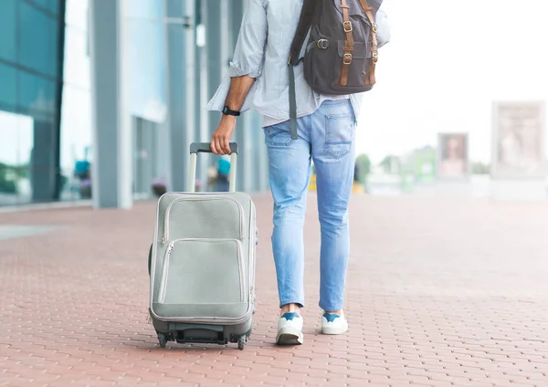 Efter ankomsten. Oigenkännlig man med resväska och ryggsäck promenader nära flygplatsen — Stockfoto