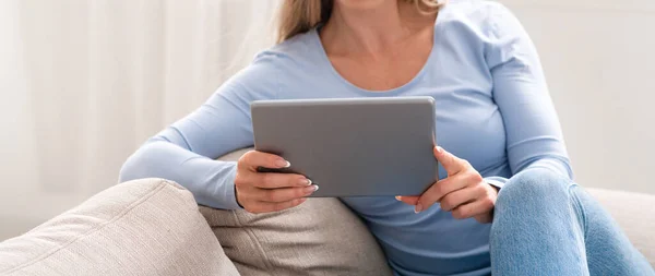 Nachrichten lesen und Videos auf dem Tablet ansehen. Frau mit Gerät sitzt auf Sofa — Stockfoto